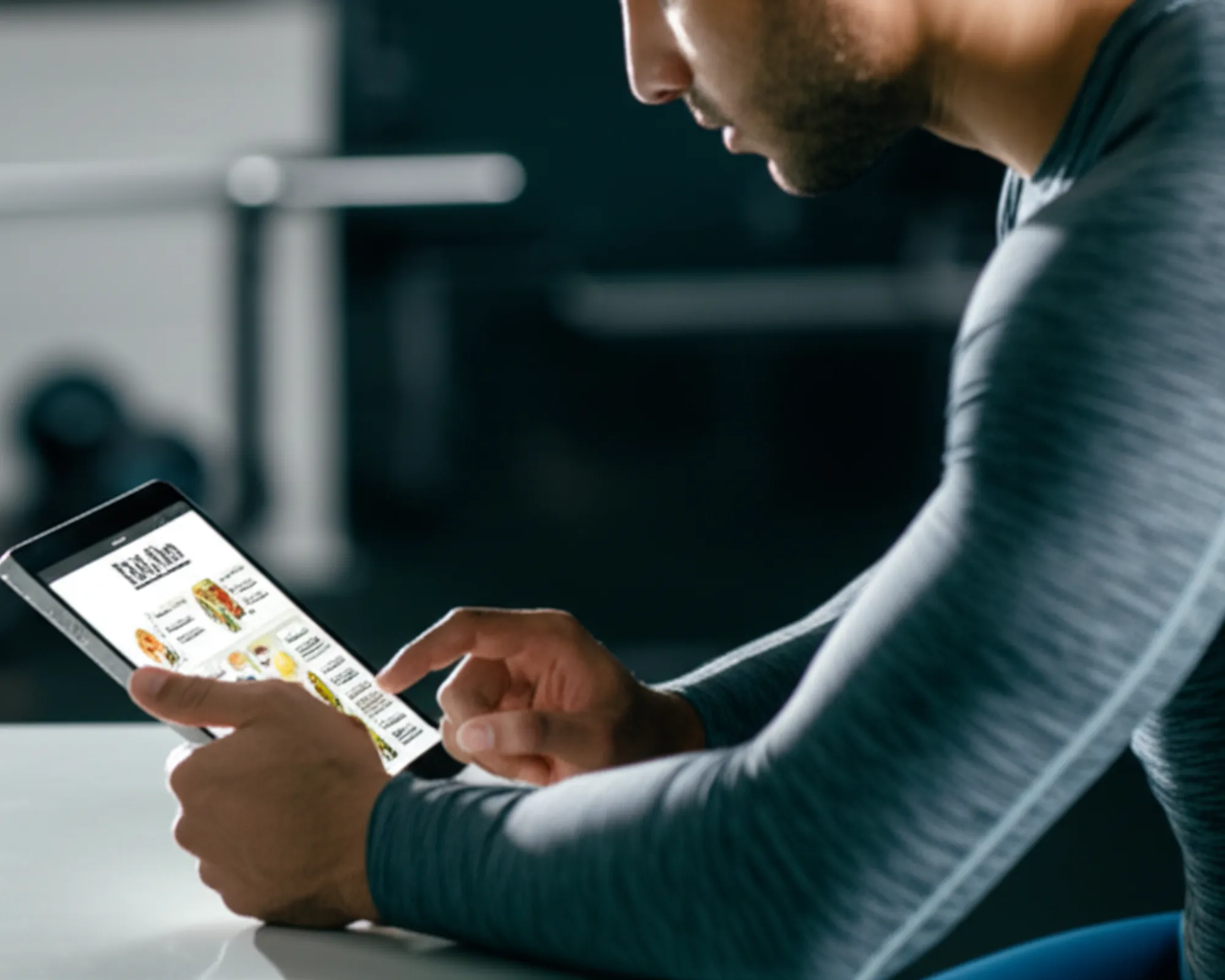 An athlete reviewing their macronutrient intake on a tablet in a gym setting, symbolizing nutrition for muscle growth.